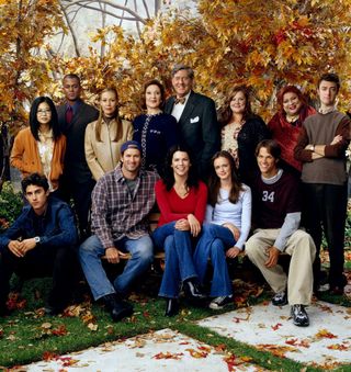 the cast of gilmore girls poses together by autumn leaves