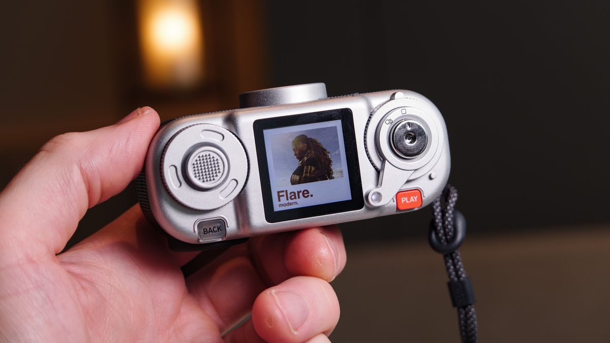 Fujifilm Instax Pal 2 digital camera in user's hand, looking at the top LCD screen