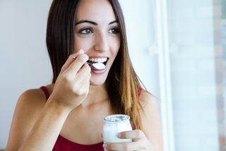 A young woman eats yogurt.