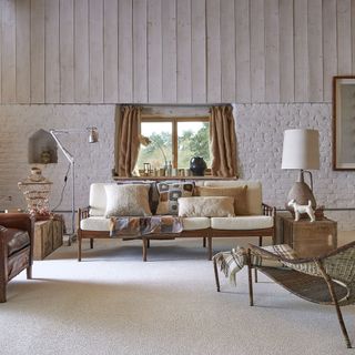 A neutral living room scheme in a country home with rustic wall panels
