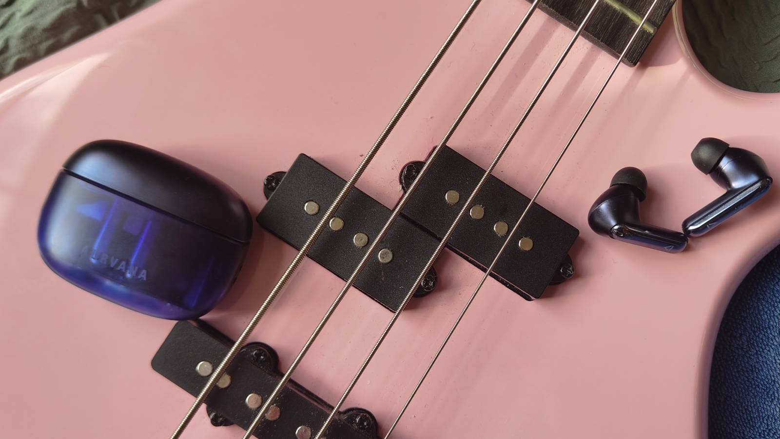 The Creative Aurvana Ace 3 buds and case on a pink bass guitar.