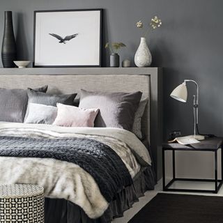 grey bedroom with large double bed, faux fur throw, cushions, headboard display and bedside table