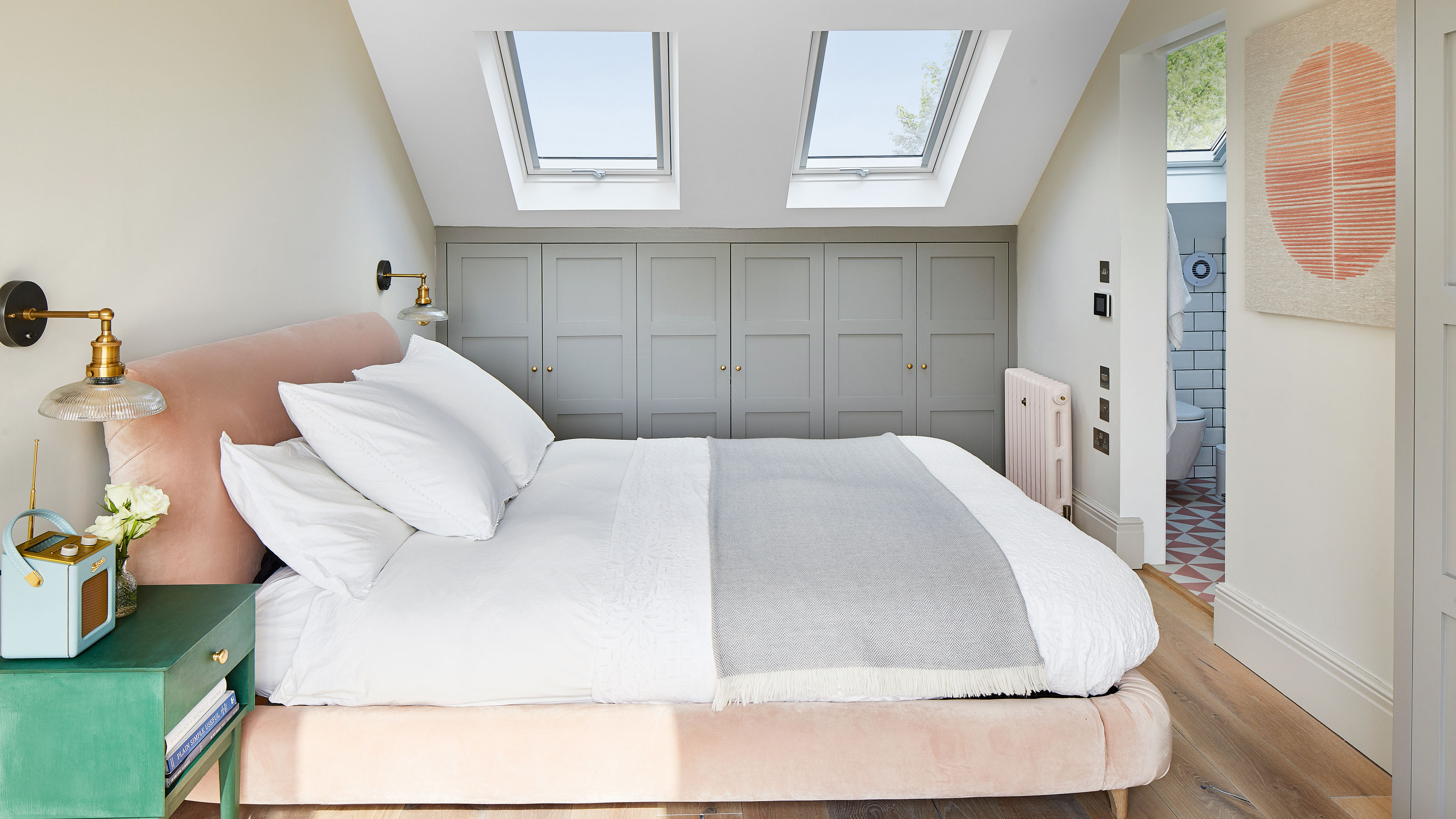 Bedroom with grey run of wardrobes and a pink bed