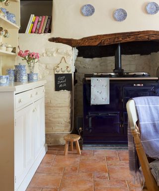 A country style kitchen with terracotta floor tiles and a black Aga