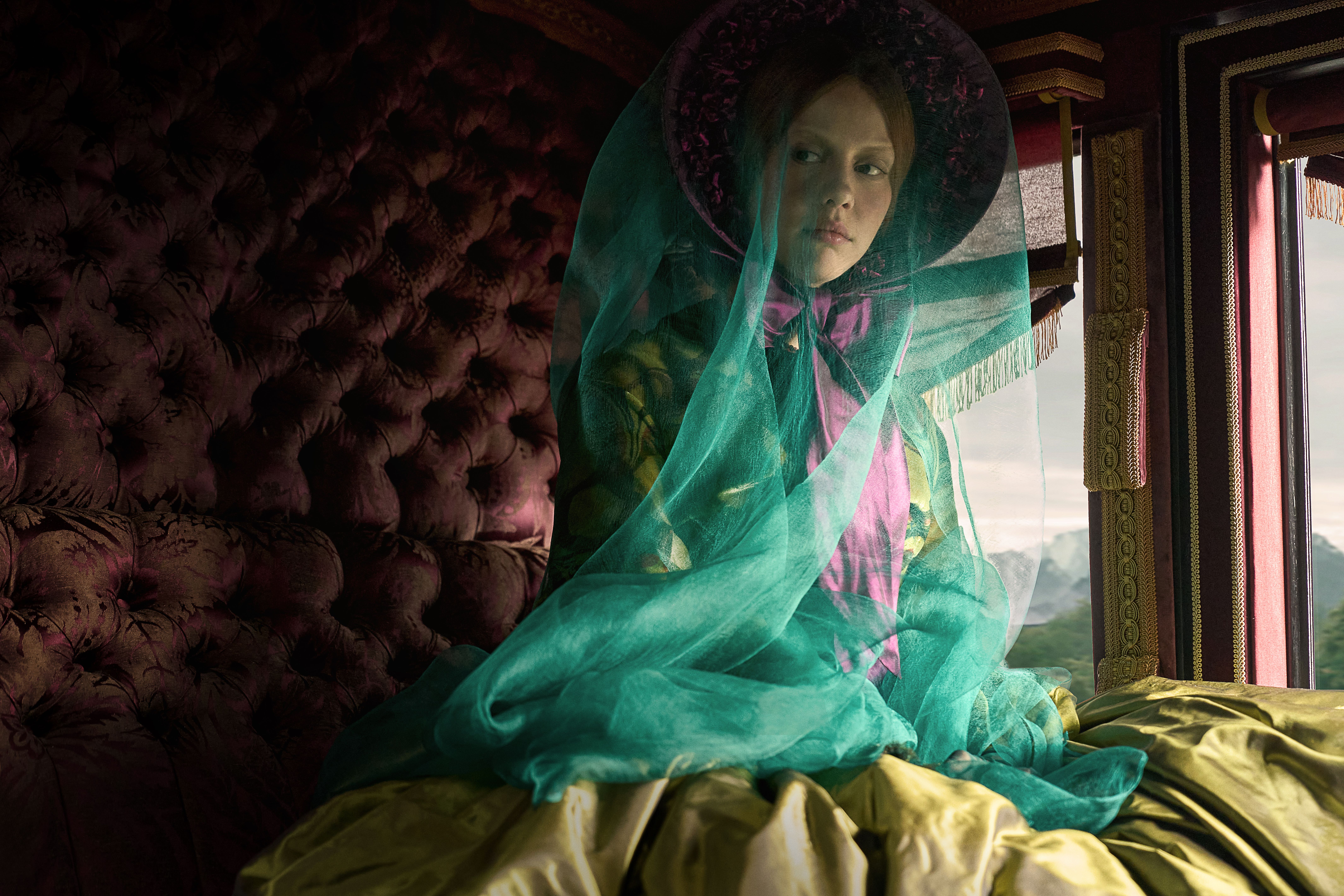 mia goth as elizabeth wearing a green sheer vail in the back of a carriage in frankenstein