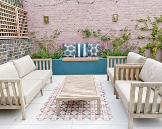 Small outdoor living room with pink brick wall, blue painted render and blue floor tiles