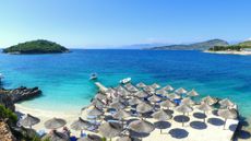 Sandy beach, with beach umbrellas, and clear blue sea of Ksamil, Albania