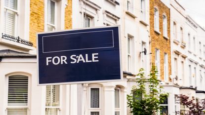 a for sale sign in front of a row of houses