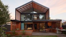 house with slated timber gable roof and side panels over first floor balcony