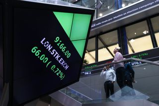 Traders look at the ticker in the London Stock Exchange (Photographer: Hollie Adams/Bloomberg via Getty Images)