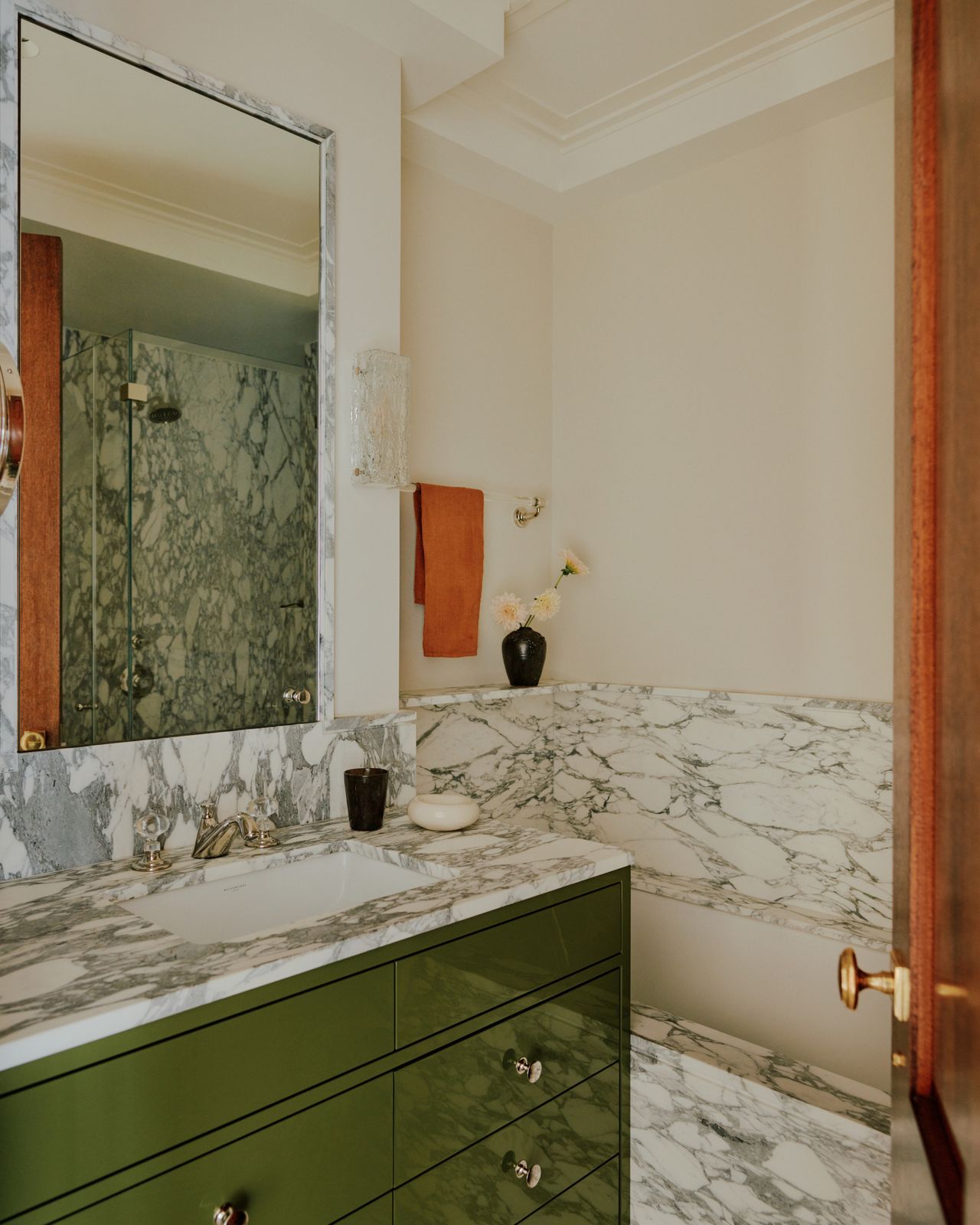 A full bath with a green vanity topped with a white stone