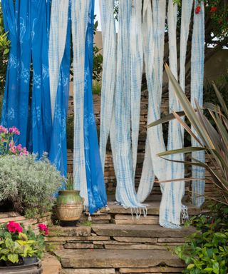 Fabrics from a collection created by Lisa Fontanarosa and artist Kaveri Singh hanging in a garden