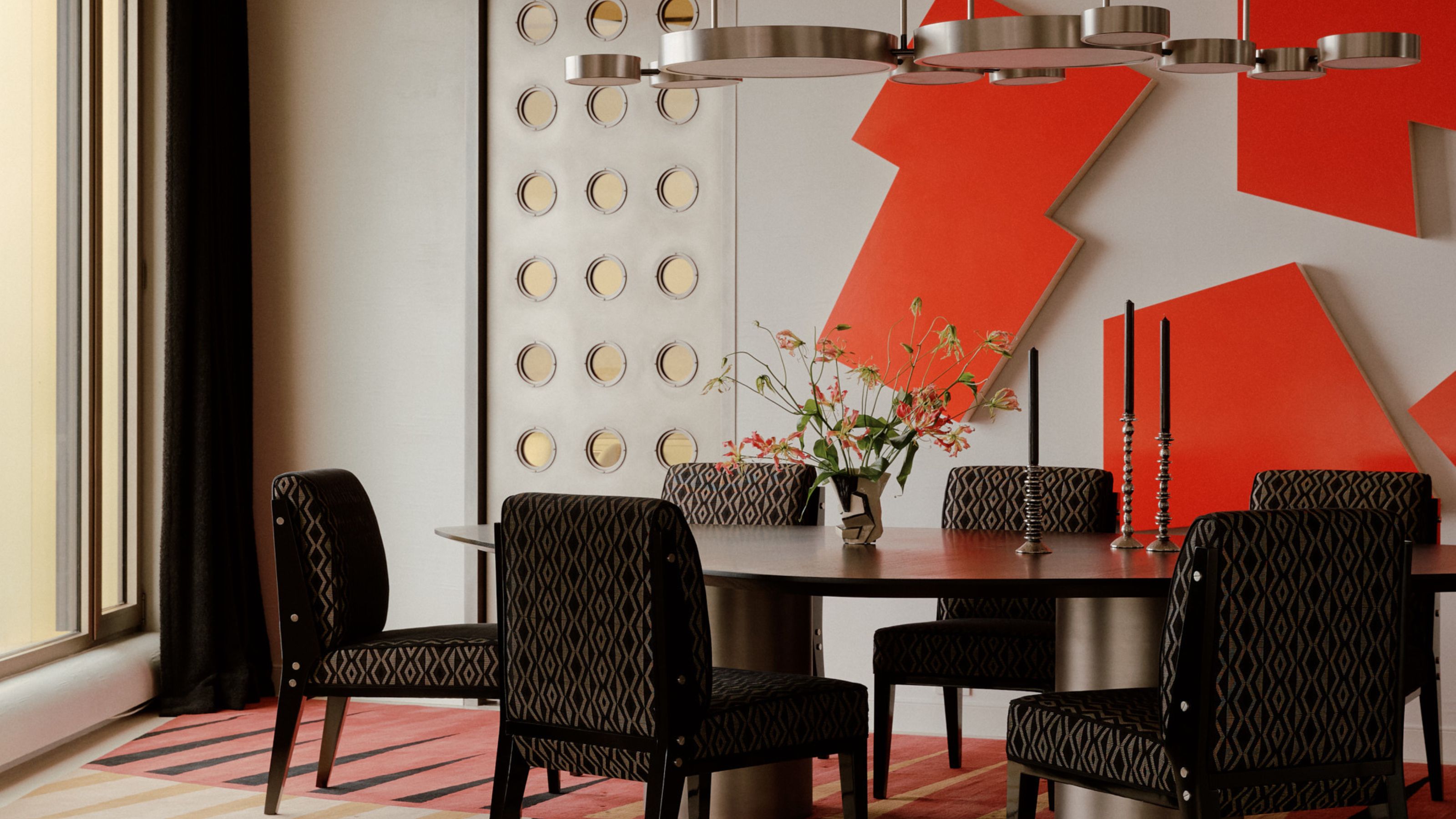 modern dining room with red sculptures on wall, silver pendant light, black upholstered dining chairs, and door with portholes