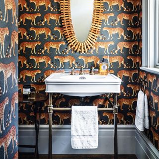 downstairs toilet with leopard print wallpaper and wood mirror