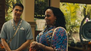 Dom Hetrakul as Pornchai and Natasha Rothwell as Belinda in The White Lotus season three. They are in the hotel's spa with lush green vegetation visible in the background. Pornchai is wearing massage scrubs, while Natasha is in casual clothes. 