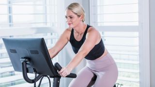 Woman riding exercise bike at home