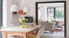 White dining area with a black archway through to a living room beyond