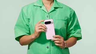 A person in a green shirt holding up the Google Pixel 9 Pro