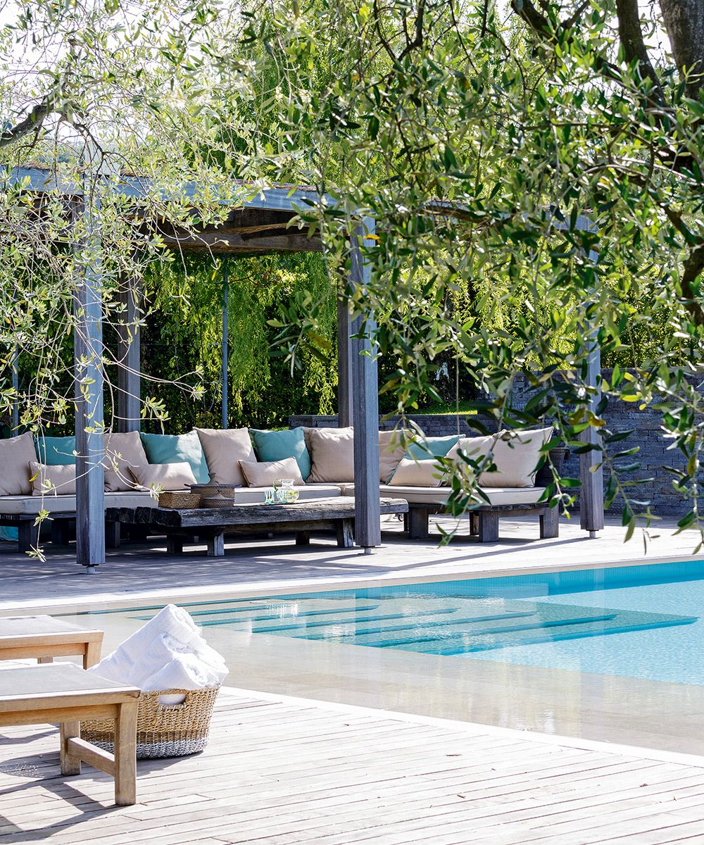 A pool area with a sheltered patio area and a large outdoor sofa