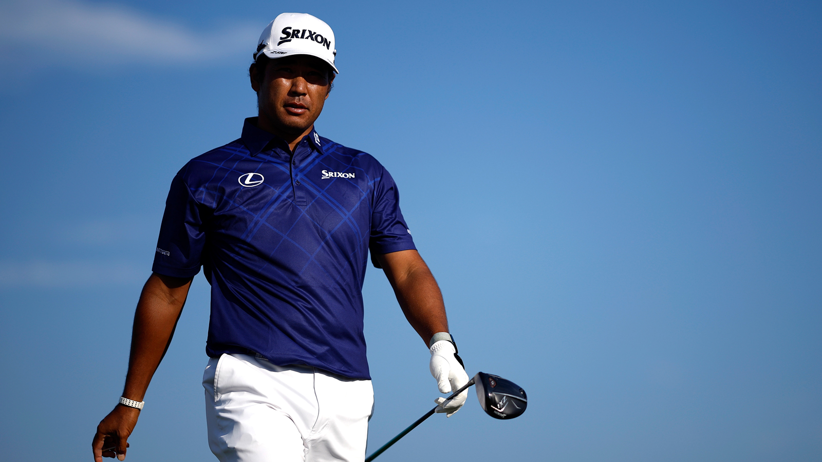 Hideki Matsuyama walks off the tee holding a driver