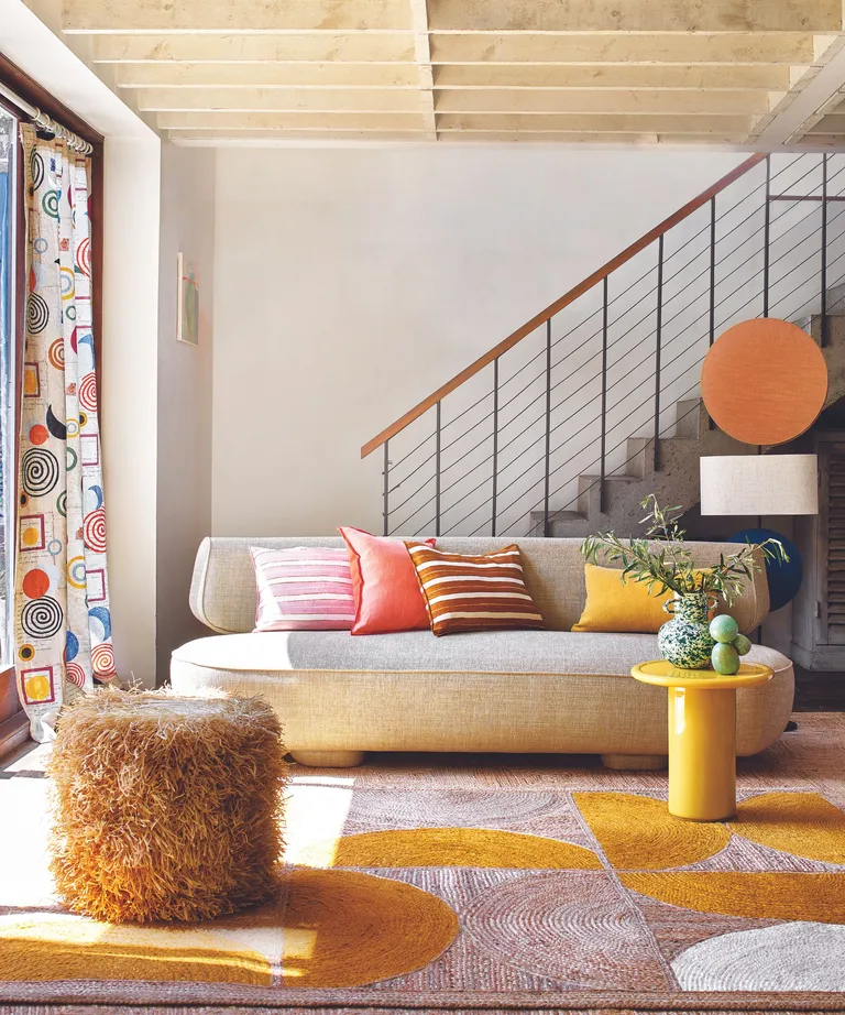 Grey sofa, yellow, pink and white carpet, fluffy orange footstool