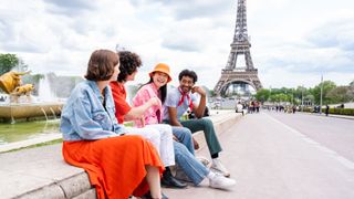 A group of people talking in front of the Eiffel Tower