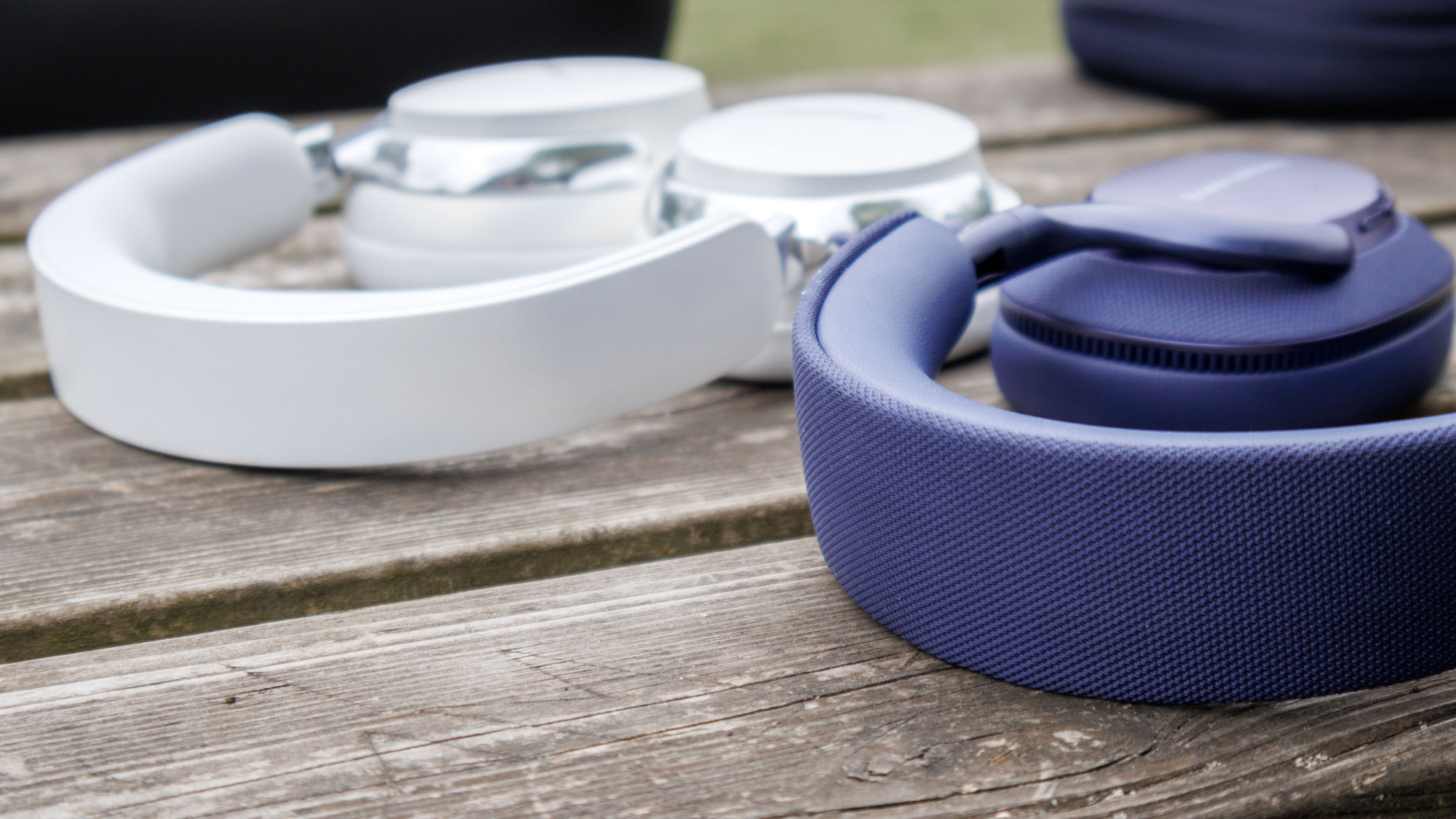 Bowers & Wilkins Px7 S3 vs Bose QuietComfort Ultra Headphones on a wooden surface, a closeup of the headbands