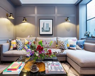 sofa arranging mistakes, small grey living room with sectional, panelled walls, wall lights, coffee table, flowers, artwork