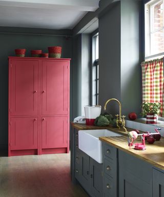 A gray with a red and green gingham drapes and a freestanding red cupboard used for freestanding kitchen cupboard storage ideas.