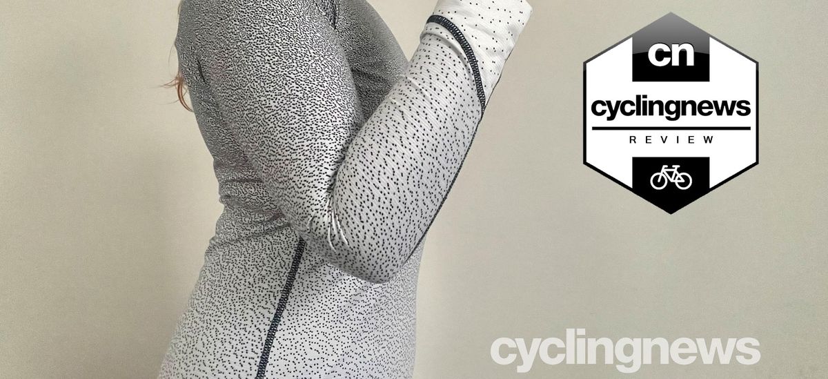 A close up side view of the reviewer&#039;s torso, wearing the black and white spotted base layer. Her arm is bent and raised, displaying the tightness of the sleeve around the elbow. A black and white &#039;Cyclingnews Review&#039; badge is overlaid on the right