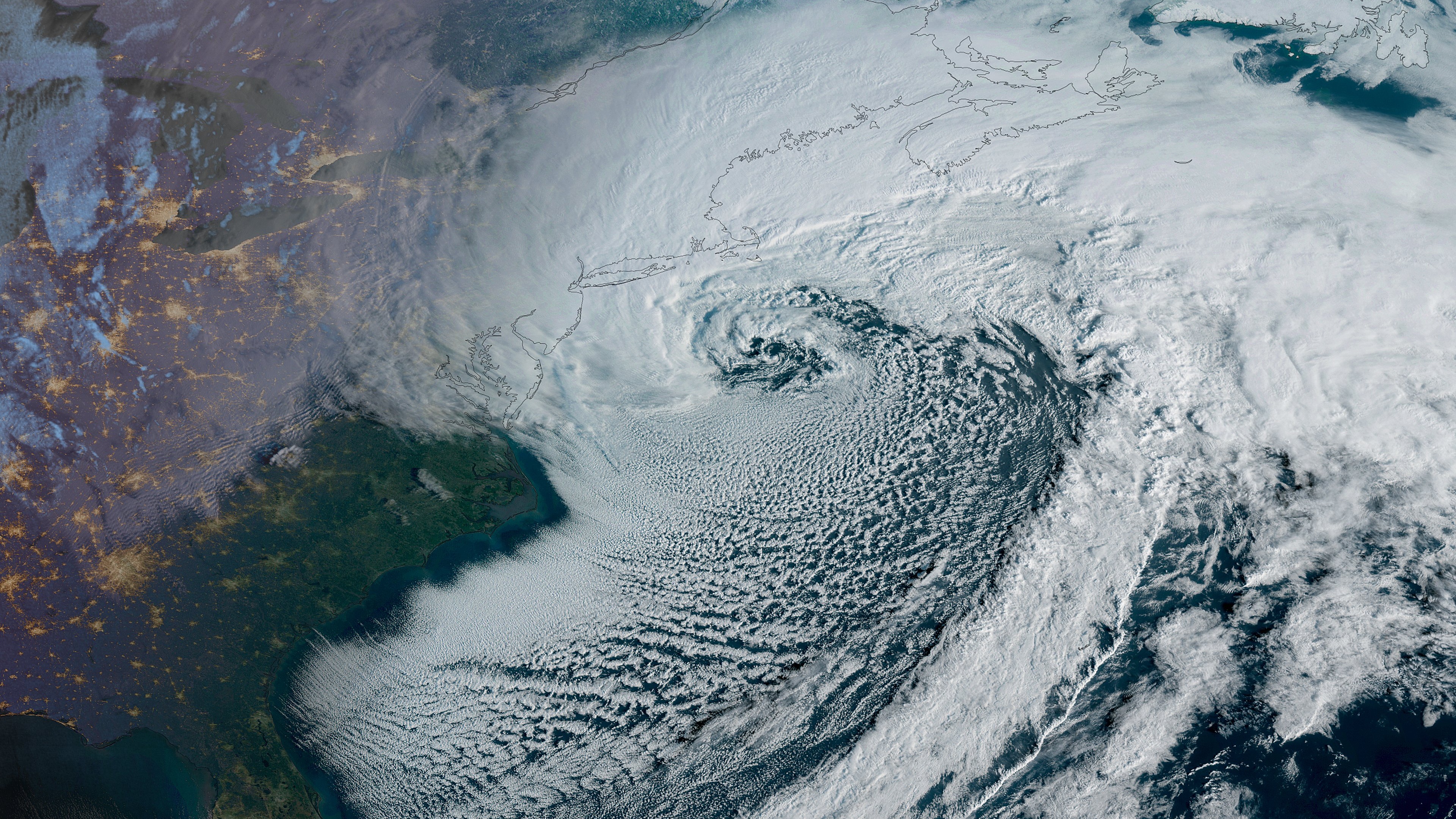 A satellite view of a large white spiral over land and sea representing the northeast U.S.