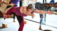 woman in a group studio setting performing a warrior 