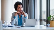 An office worker looks thoughtful while sitting at her desk in the office.