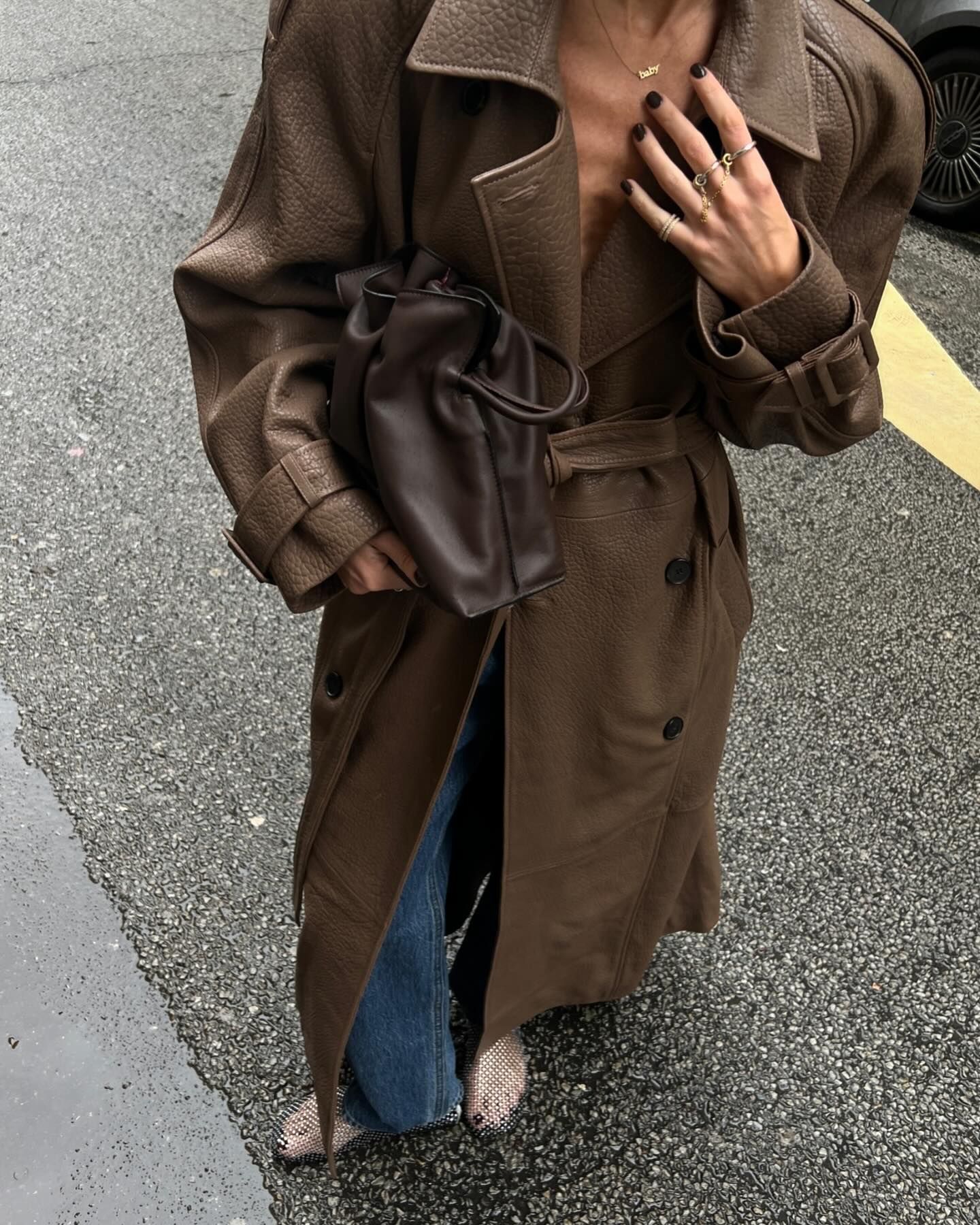 Hannah Lewis wearing a brown leather trench coat with jeans and fishnet flats