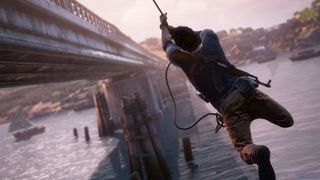 Huvudkaraktären i Uncharted 4: A Thief's End slungar sig i ett rep längs en bro.