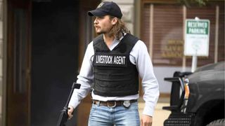 Kayce Dutton wears a livestock agent vest while carrying a gun