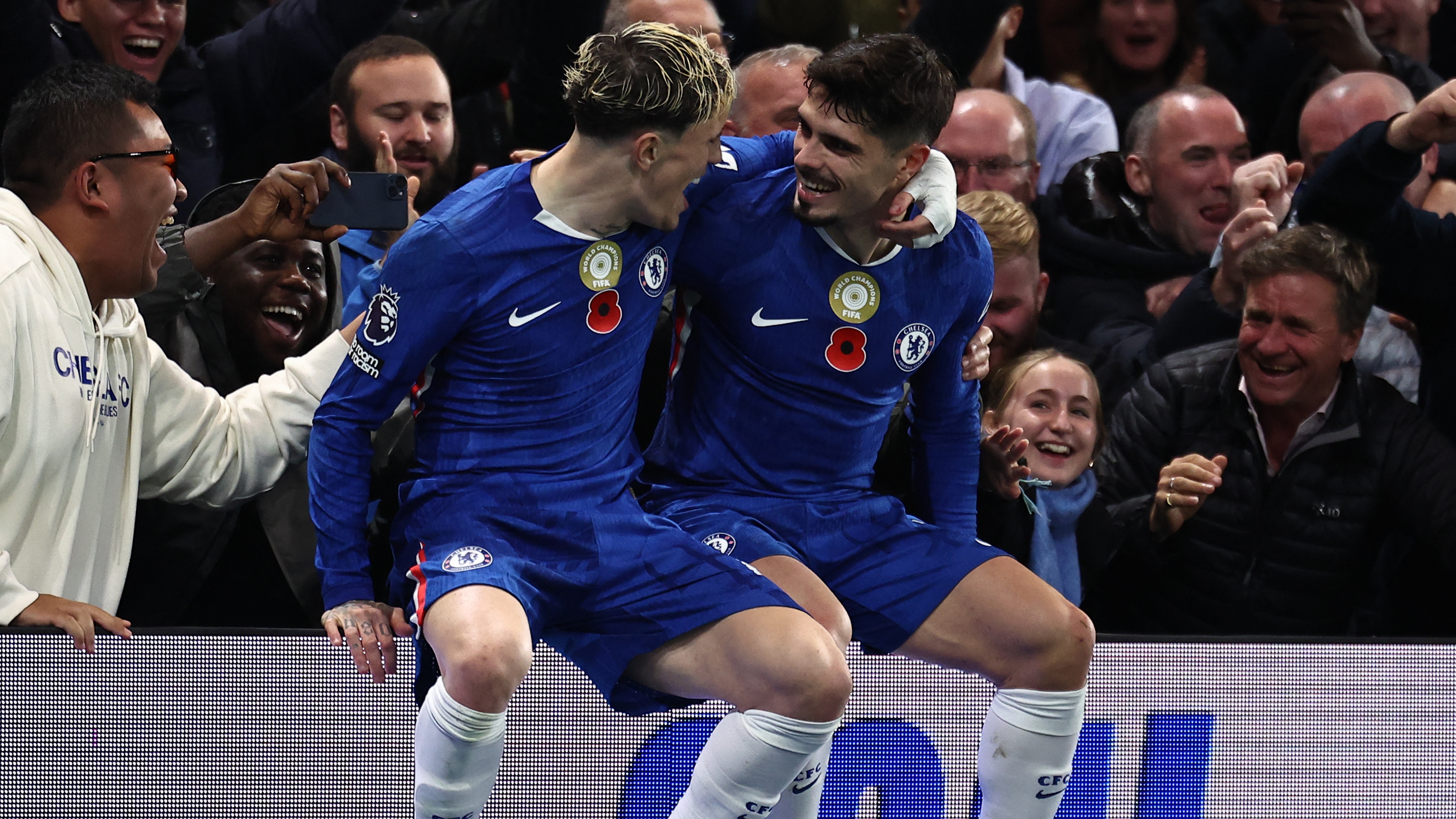 TOPSHOT - Chelsea&#039;s Portuguese midfielder #07 Pedro Neto (R) sits on the advertising boards with Chelsea&#039;s Argentinian midfielder #19 Alejandro Garnacho (L) as he celebrates scoring their third goal for 3-0 during the English Premier League football match between Chelsea and Wolverhampton Wanderers at Stamford Bridge in London on November 8, 2025.
