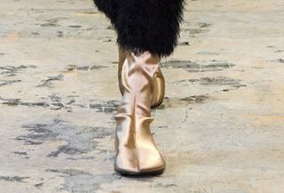 Model wearing silk sock shoes on the runway.