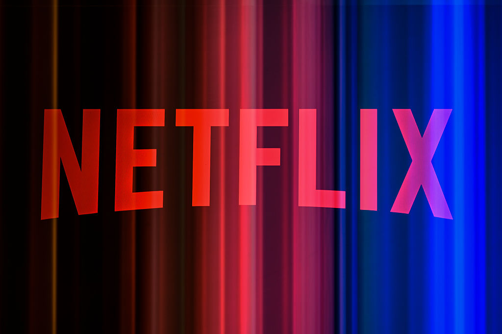 The Netflix logo is photographed using a double exposure with a promotional image featuring a color gradient in the background.