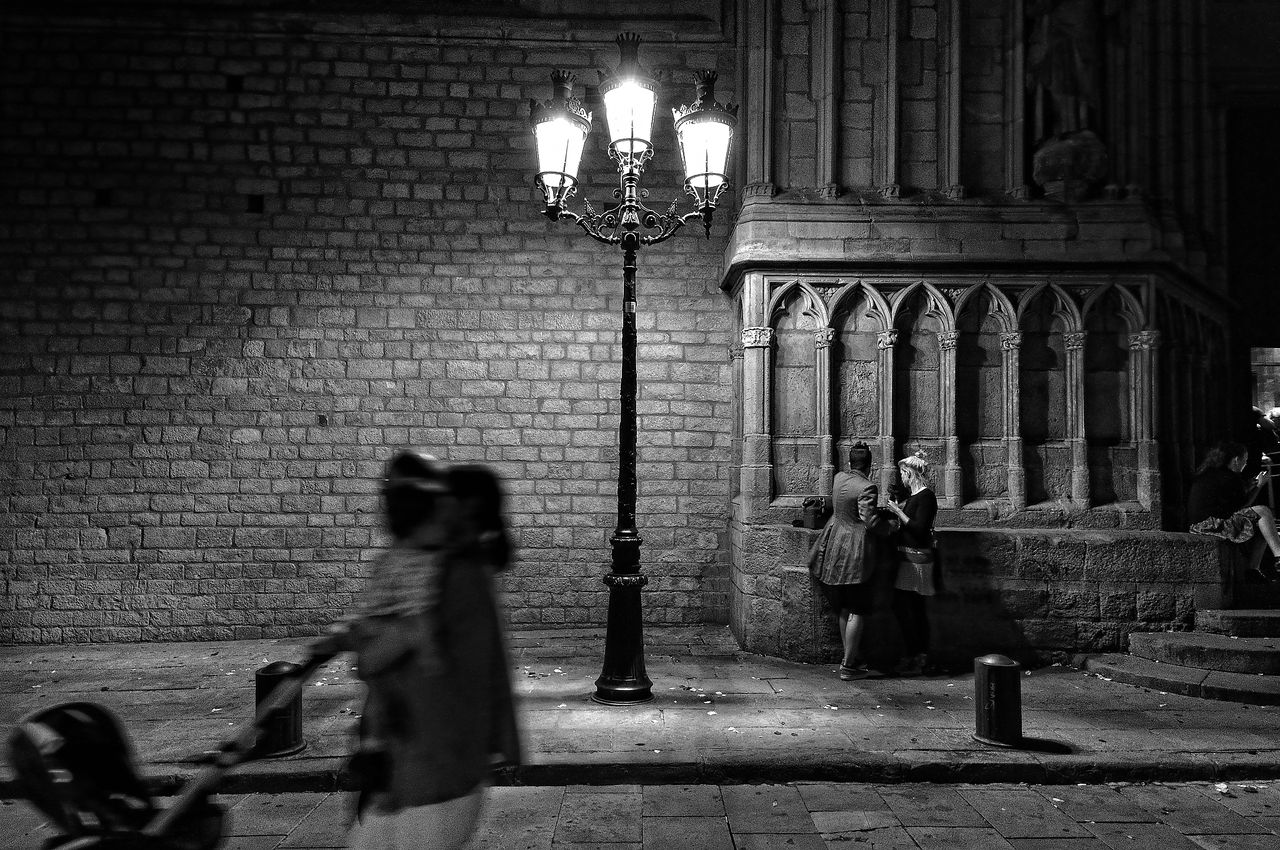 Black and white image of people walking past a street light captured on the streets of Barcelona