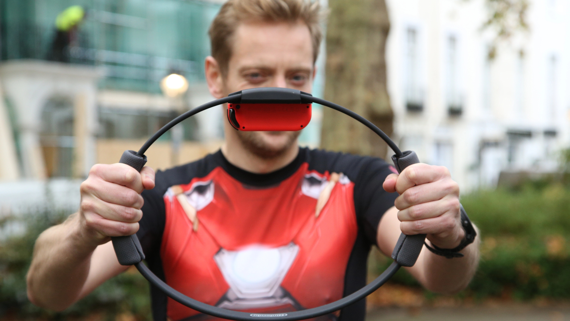 En man som står utomhus och håller upp en ring till Ring Fit Adventure.