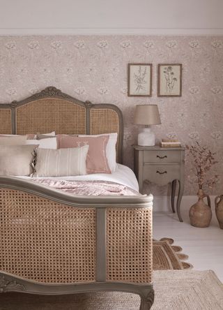 picture of double bed in a pinky neutral room, with bedside table and two rugs