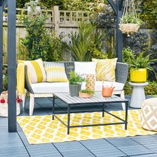 Black pergola with garden sofa sat on black decking tiles