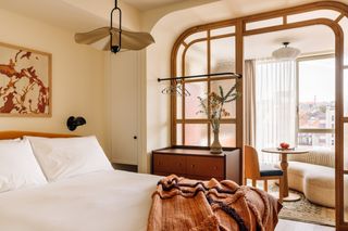 A brown-hued bedroom features textile wall art and minimalist interiors.