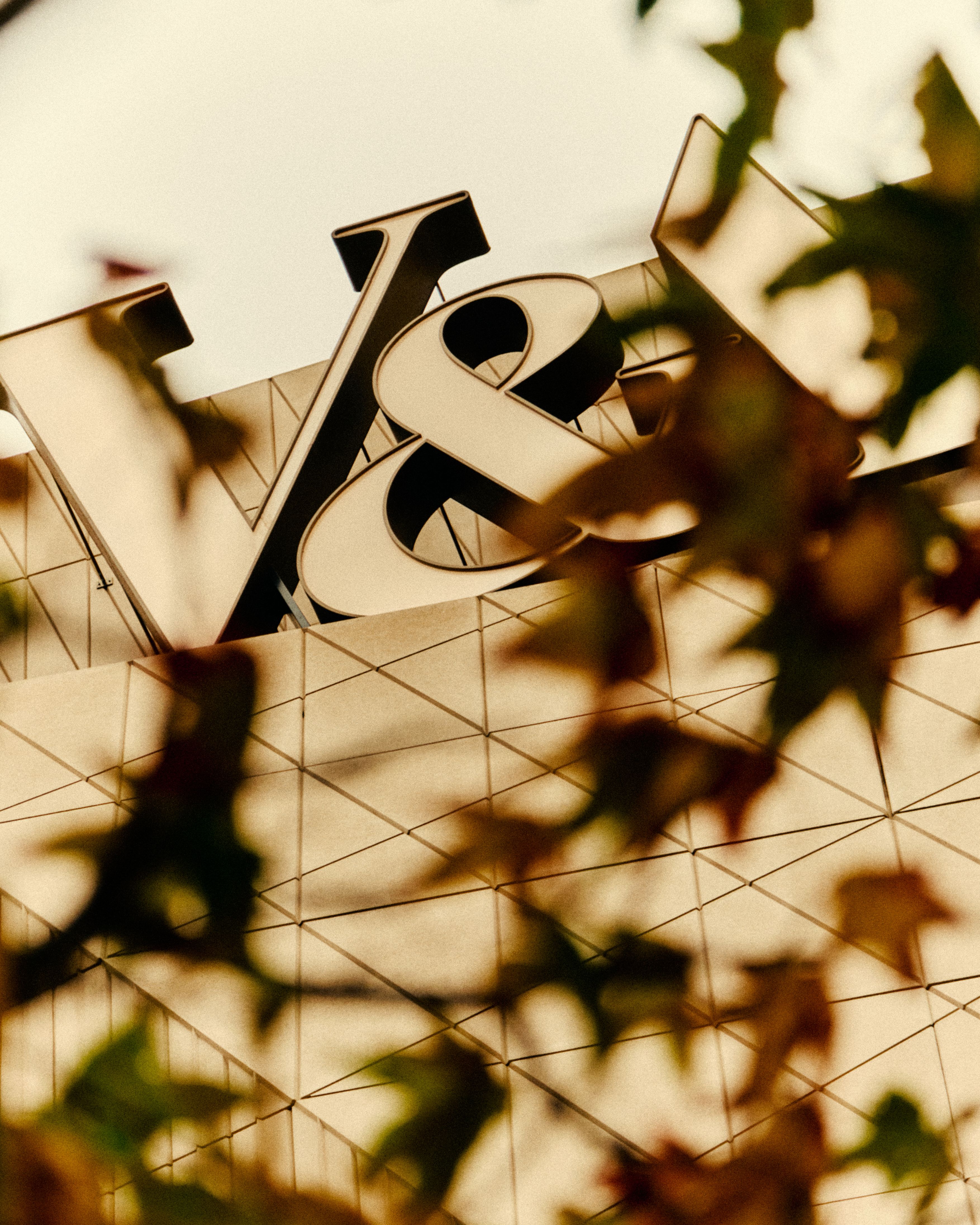Exterior view of a geometrically shaped museum facade with multiple cement slabs combined into an angular shape, with a white sign that reads, in caps, "V&amp;A".