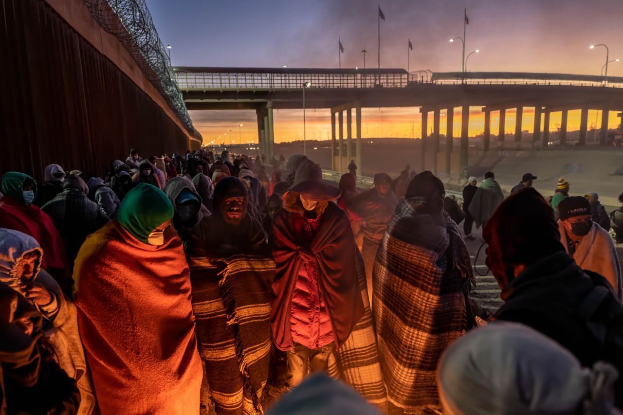 Immigrants warm themselves by a fire on the border.