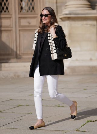 Alba Garavito Torre wears white jeans, ballet flats, a black blazer and a striped jumper over her shoulders