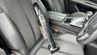 The Shark UltraCyclone Pet Pro Plus handheld vacuum resting on a car seat