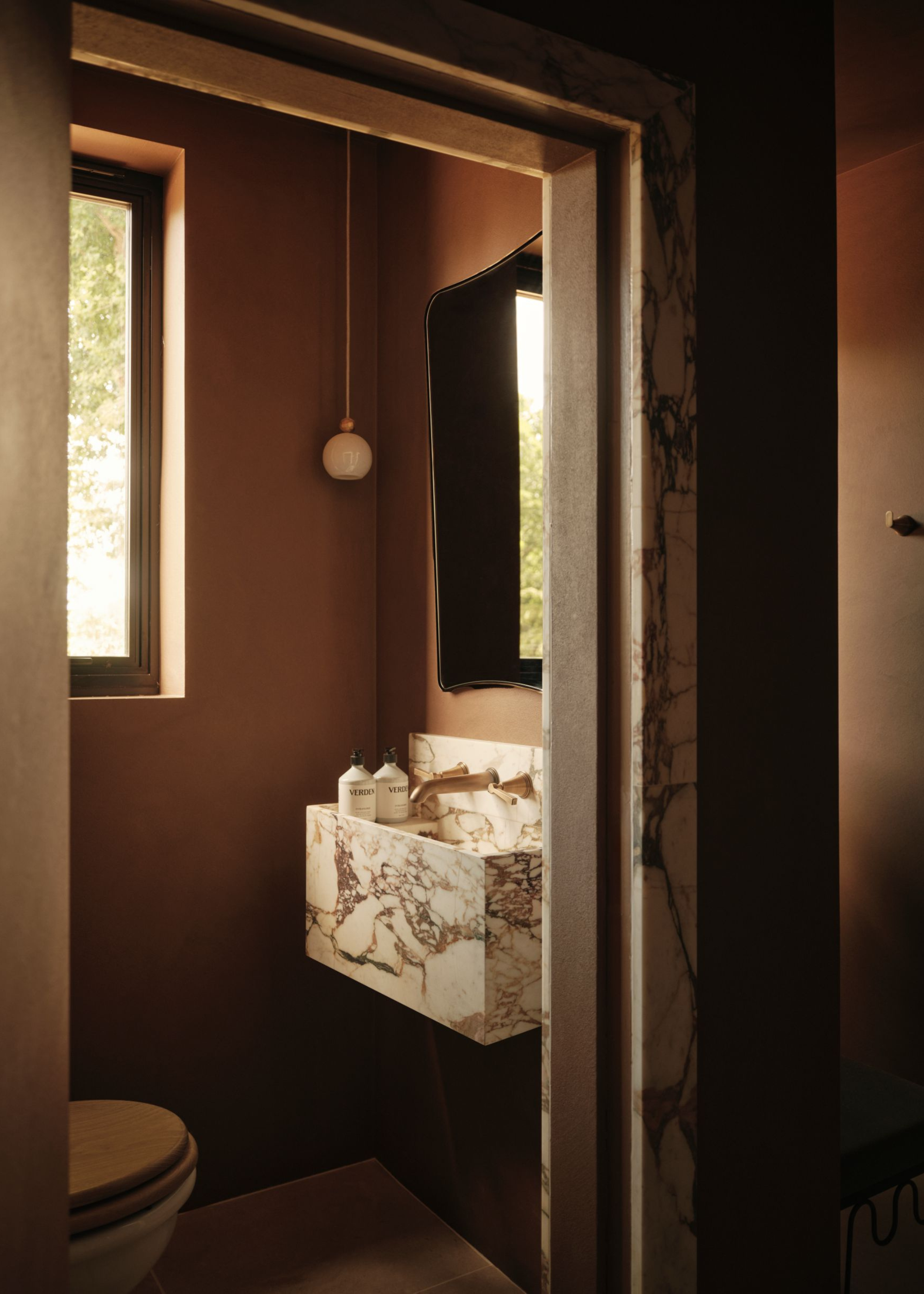 a small maroon bathroom with marble accents