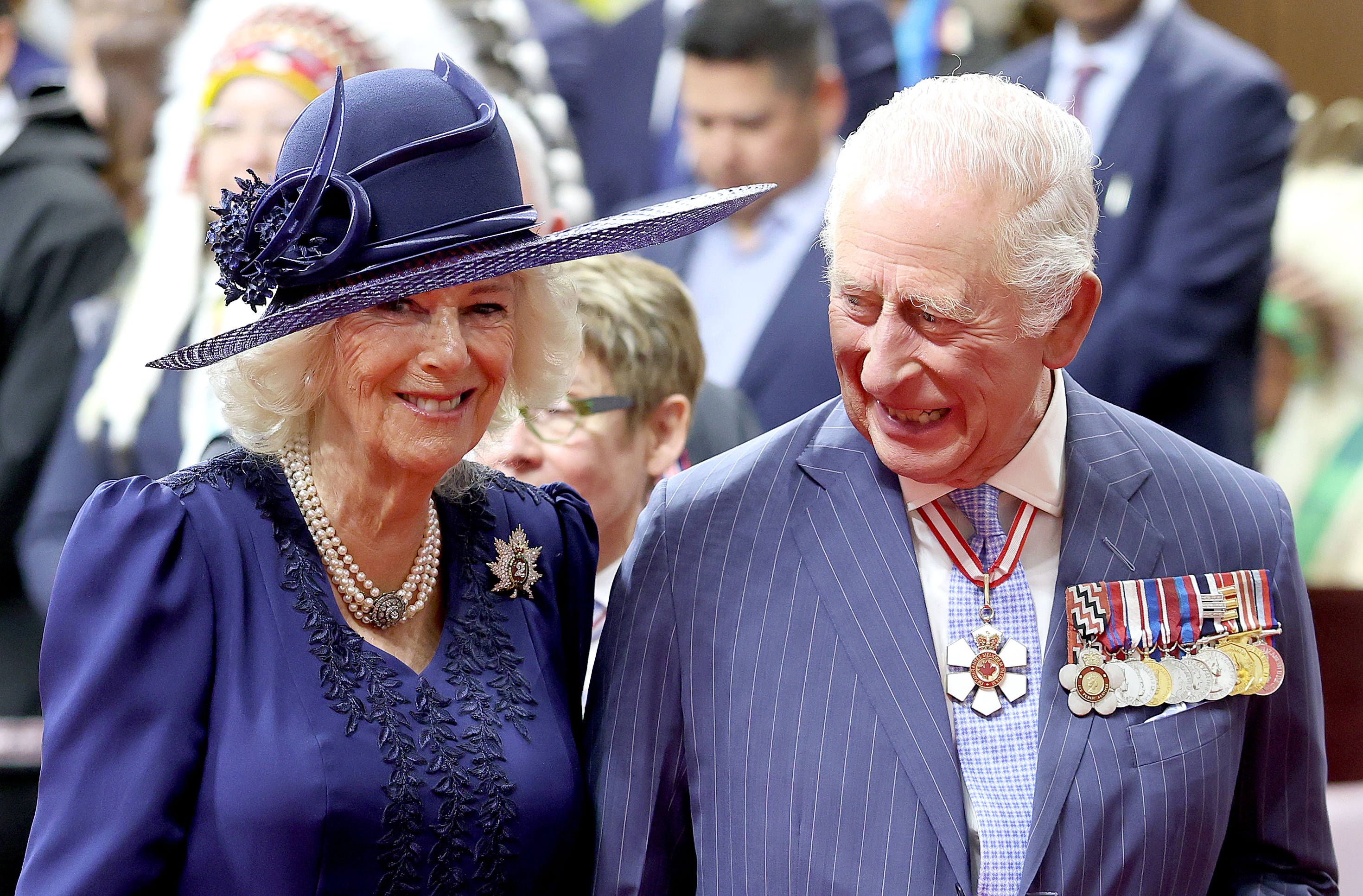 King Charles and Queen Camilla wearing blue and smiling in Canada